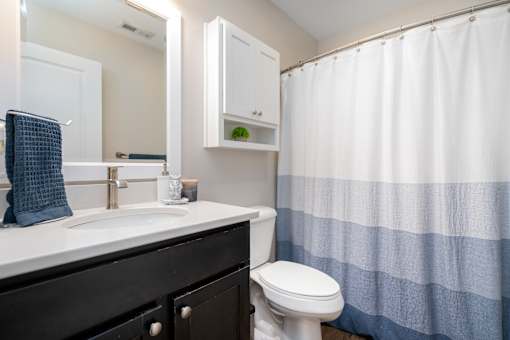 A white sink with a blue towel and a white toilet in a bathroom.