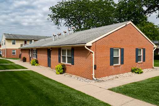 A red brick house with a grey roof and a white door.