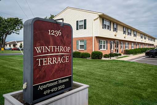 A sign for Winthrop Terrace Apartment Homes stands in front of a building.