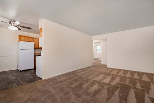 A room with a white fridge and a ceiling fan.