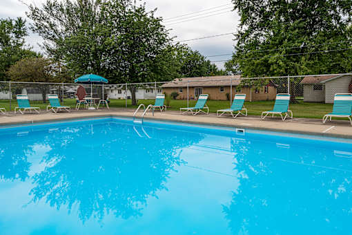 A swimming pool with blue water and a red umbrella.