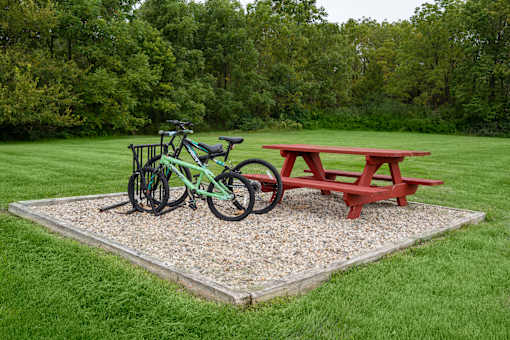 A green bike is parked next to a red picnic table.