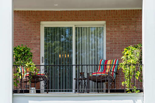 A patio with a chair and a table with a striped cushion.