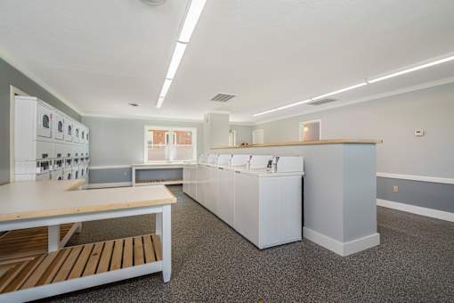 A kitchen with white appliances and a wooden table.