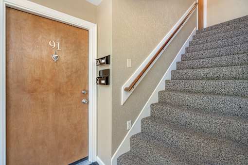 A brown door with the number 91 on it is open to a staircase.