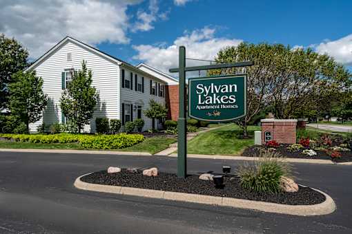 A sign for Sylvan Lakes Apartment Homes stands in front of a building.