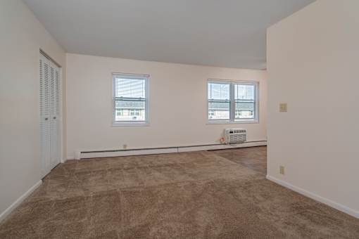 A room with a carpeted floor and two windows.
