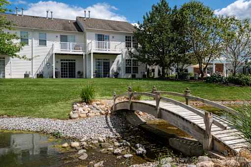 A white house with a bridge over a pond.
