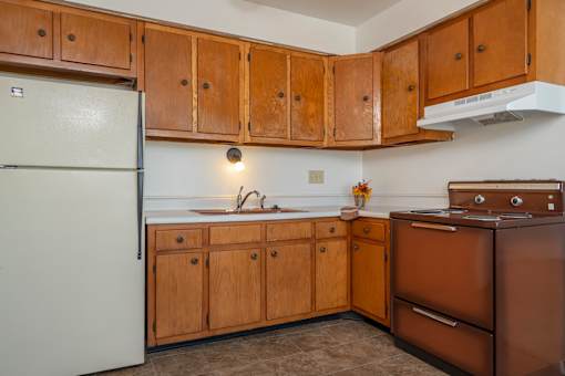 A kitchen with brown cabinets and a white refrigerator.