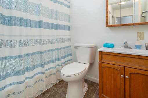 A white toilet sits next to a blue and white striped shower curtain in a bathroom.