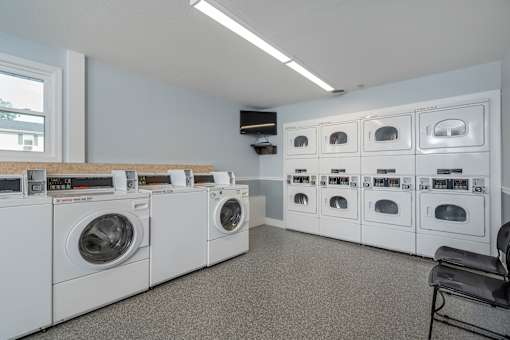A laundry room with a row of washing machines and a dryer.