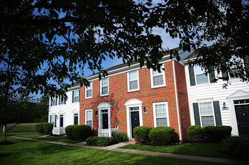 A red brick house with white trim and a black door.