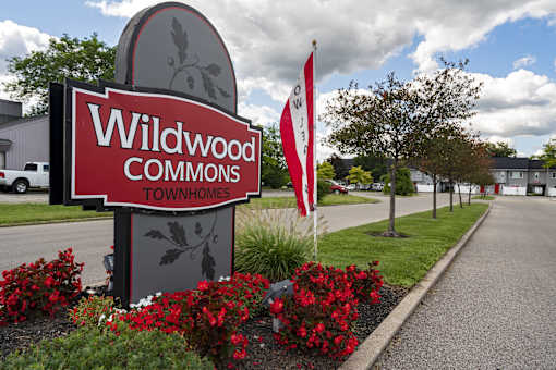 A sign for Wildwood Commons townhomes is shown in front of a building.