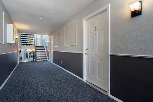 A hallway with a white door and a staircase.