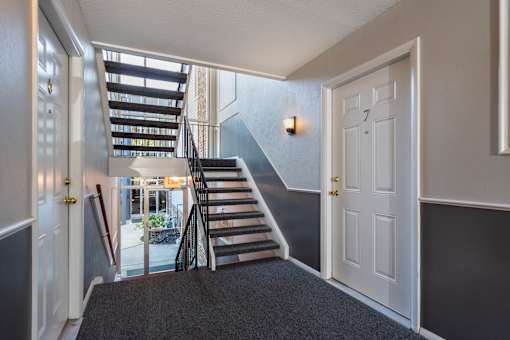 A staircase with a black carpeted floor leads to the second floor.