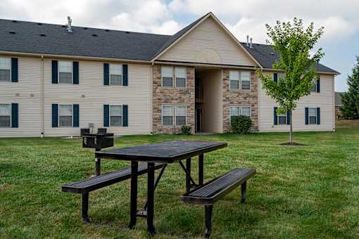 A picnic table and bench in front of a building.
