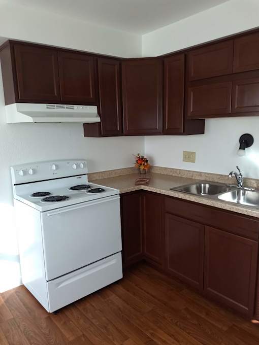 A white stove in a kitchen with brown cabinets.