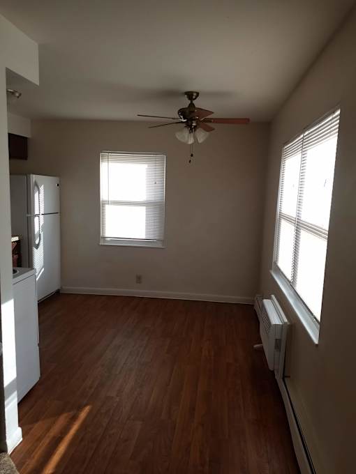 A room with a ceiling fan and two windows.