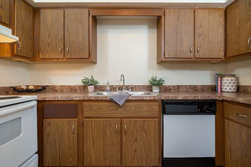 A kitchen with wooden cabinets and a white dishwasher.