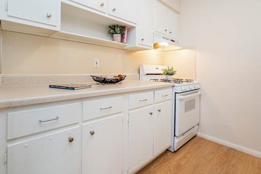 A kitchen with white cabinets and a stove top oven.