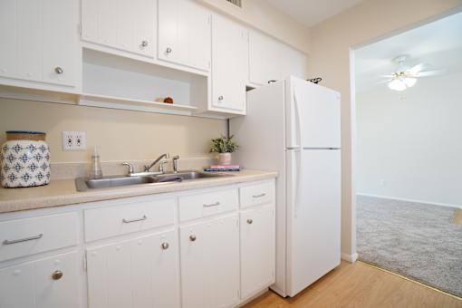 A kitchen with white cabinets and a white refrigerator.