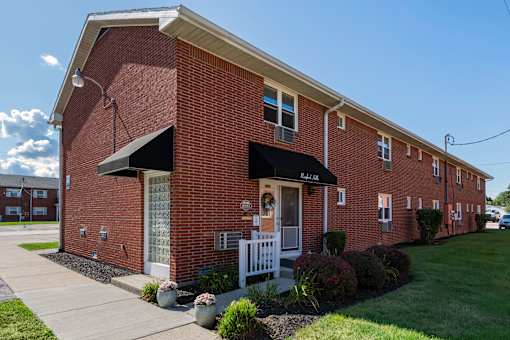 A red brick building with a white door and a black awning.