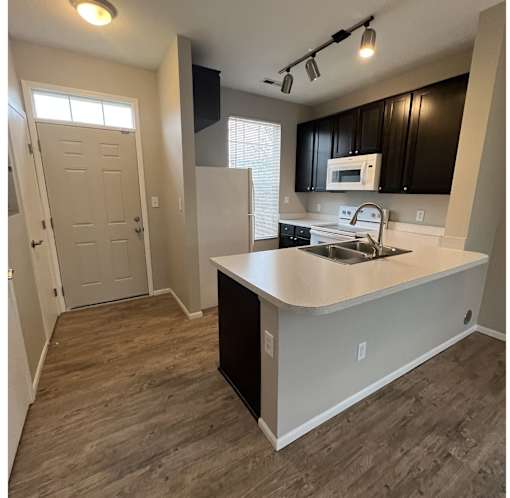A kitchen with a white counter top and black cabinets.