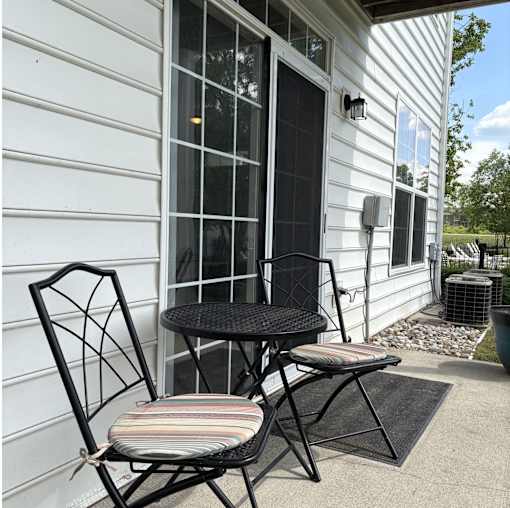 A black metal chair with a striped cushion sits on a patio.