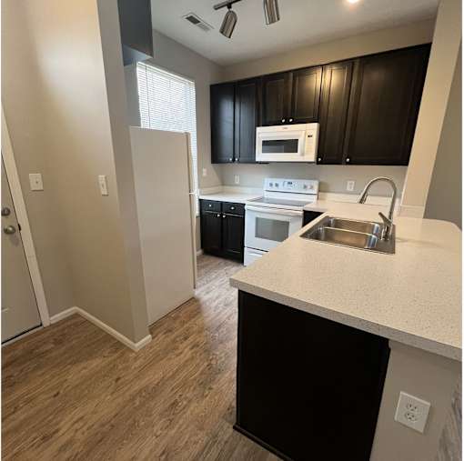 A kitchen with black cabinets and a white counter.
