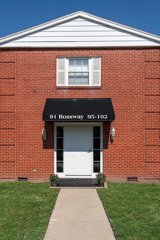 A red brick building with a black awning that reads 91 Rossway 95-102.