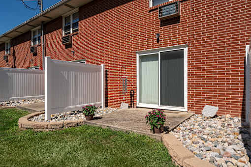 A red brick house with a white fence and a glass door.