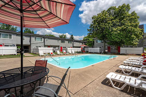 A pool surrounded by chairs and umbrellas.