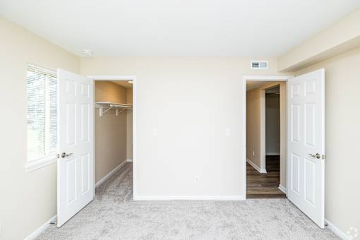 A room with two open doors and carpeted flooring.