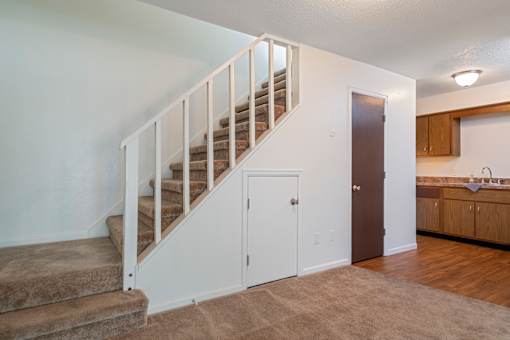 A staircase with a carpeted floor and a brown door.