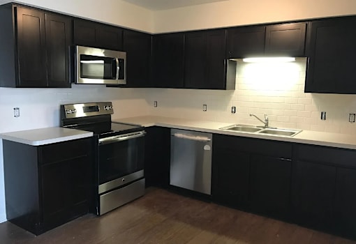 A kitchen with black cabinets and stainless steel appliances.