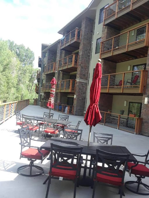 a patio with tables and chairs and two umbrellas  at Roaring Fork Apartments, Basalt, Colorado