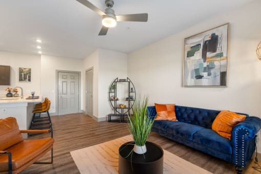 a living room with a blue couch and a ceiling fan at 41 North Apartments, Fort Wayne, IN
