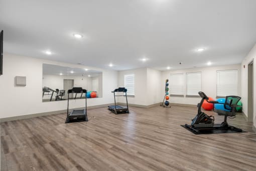 a gym with treadmills and weights in a room with white walls and floors at 41 North Apartments, Indiana, 46835