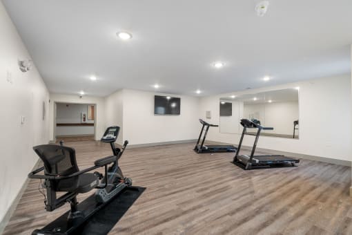 a gym with two exercise machines and a tv on the wall at 41 North Apartments, Fort Wayne, IN