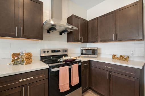 a kitchen with brown cabinets and stainless steel appliances and white countertops at 41 North Apartments, Fort Wayne