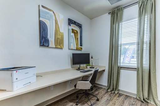 A room with a desk, chair, and two paintings on the wall.