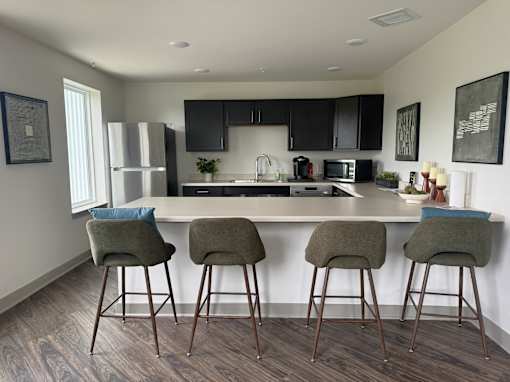 A kitchen with a bar area and three bar stools.