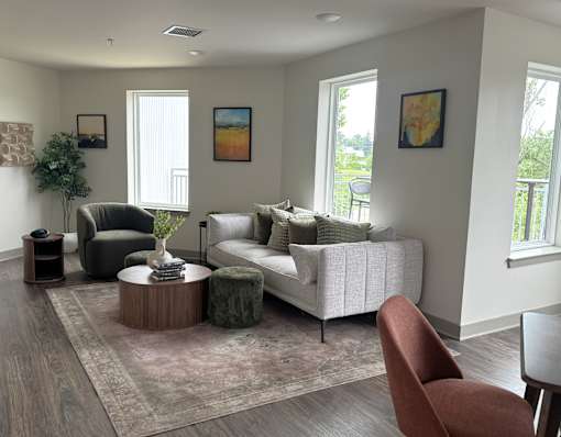 A living room with a white couch, a green chair, and a brown ottoman.