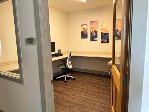 A computer room with a desk and a chair.