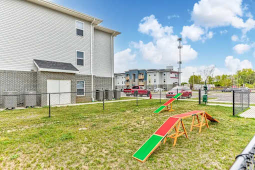 A playground with a red slide and a green slide in front of a grey building.