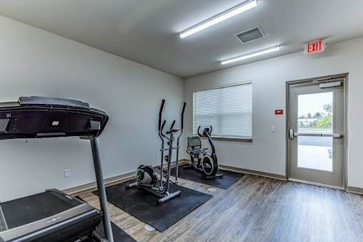 A gym room with a treadmill, elliptical trainer and a stationary bike.