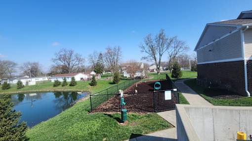 A park with a playground and a pond in the background.