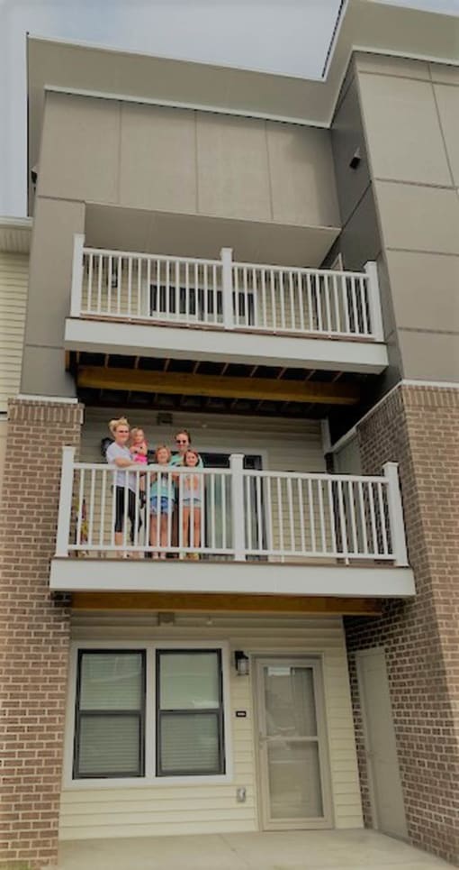 a family standing on the balcony of a building  at Gladstone Apartments, Columbus, IN, 47201