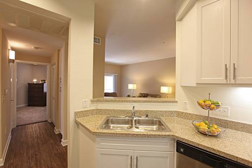 A kitchen with a sink and a bowl of fruit on the counter.