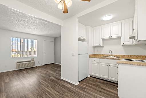 A kitchen with white cabinets and a white refrigerator.